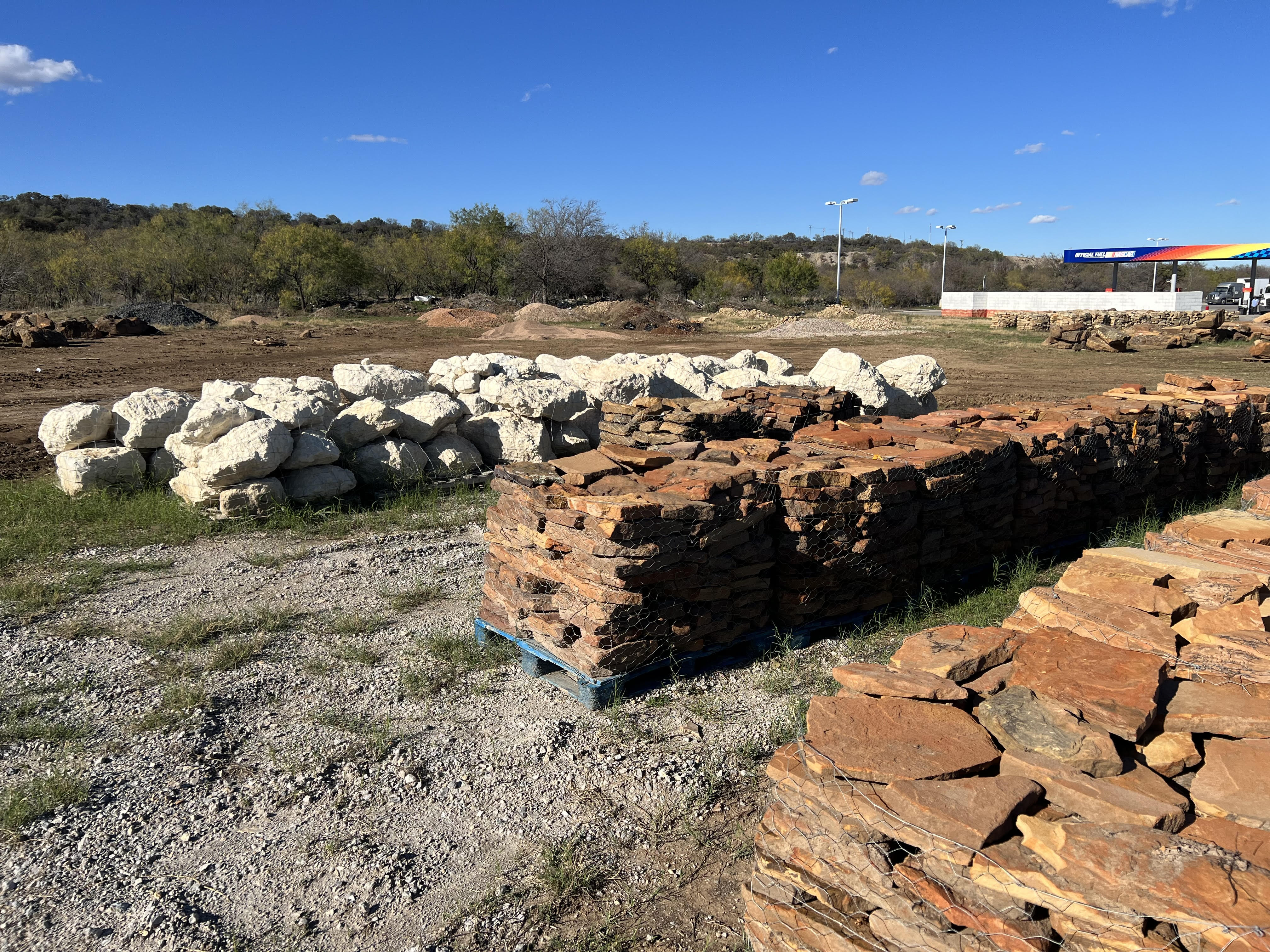 Large natural boulders and accent stone staged for landscape delivery at Trees Forever Nursery