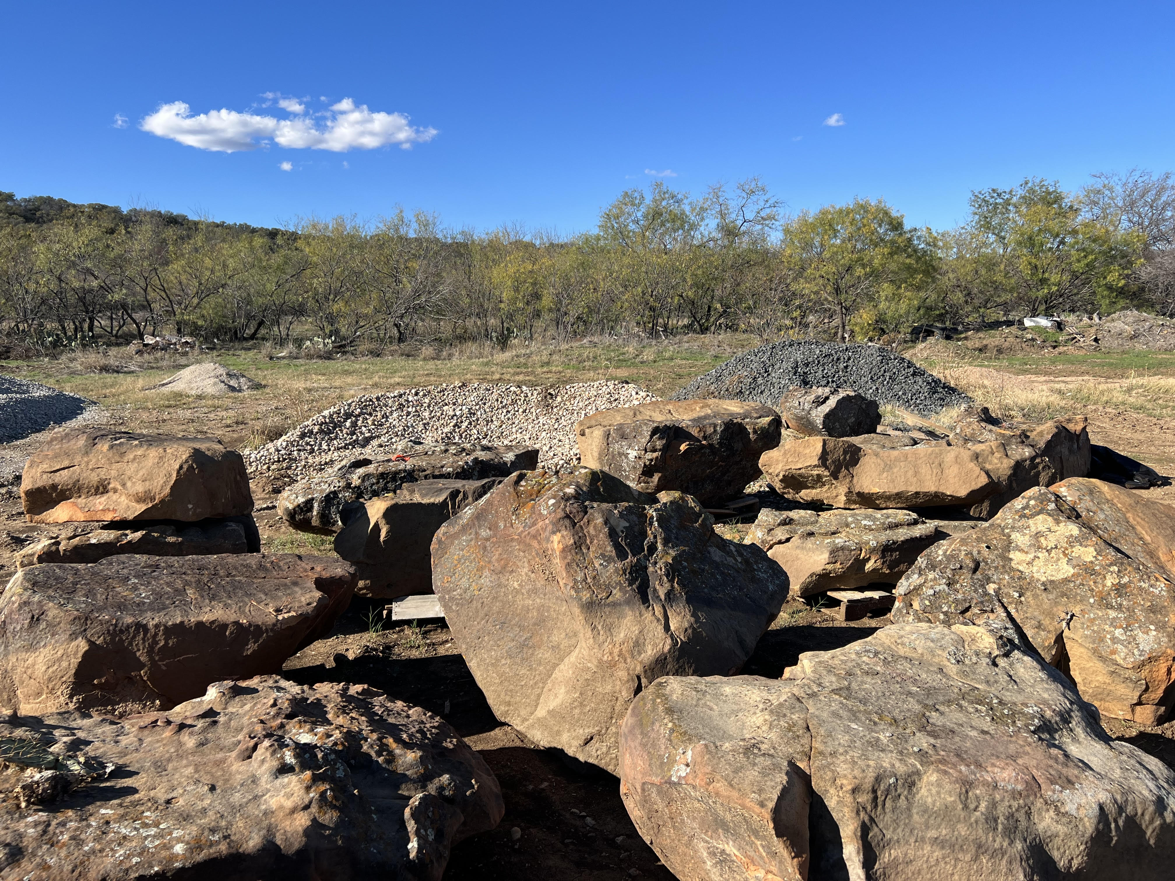 Assorted boulders and gravel piles in the Trees Forever Nursery landscape supply yard in Brownwood, TX