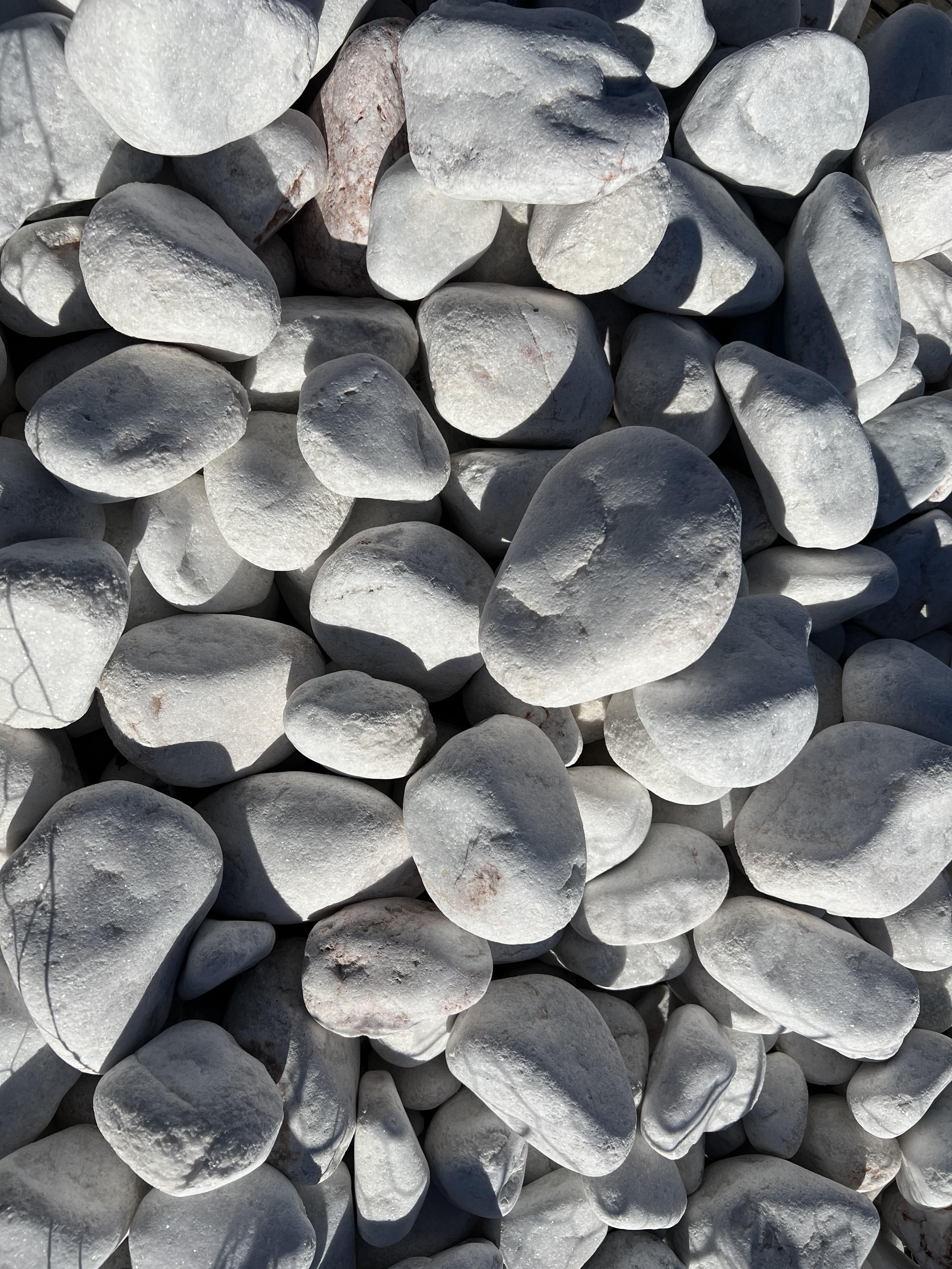 Close-up of smooth white landscape pebbles sold by the yard at Trees Forever Nursery in Brownwood, TX